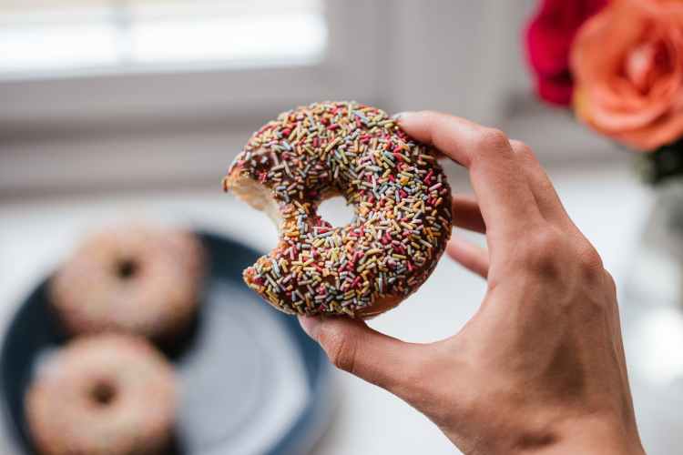 person holding doughnut with sprinkles